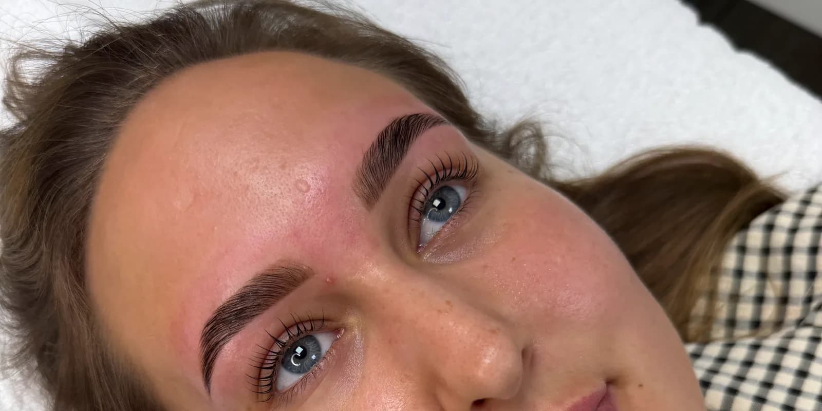 Gevormde, omhoog gelegde wenkbrauwen en gekrulde wimpers na een brow lamination en lash lift