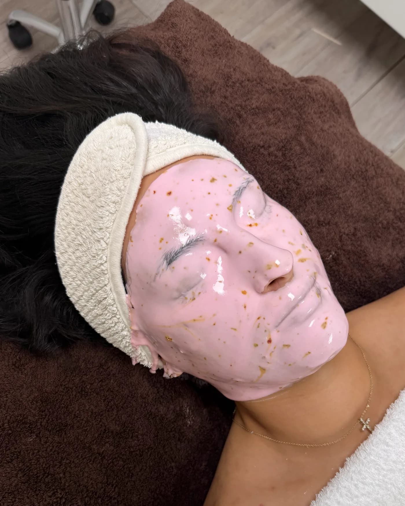 Een roze jellymasker met gouden vlokjes op het gezicht, van dichtbij